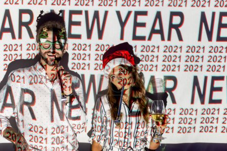 Photo for Beautiful young couple in love having fun at New Year's Eve party, dancing and blowing party whistles at midninght countdown; couple celebrating New Year in a nightclub - Royalty Free Image