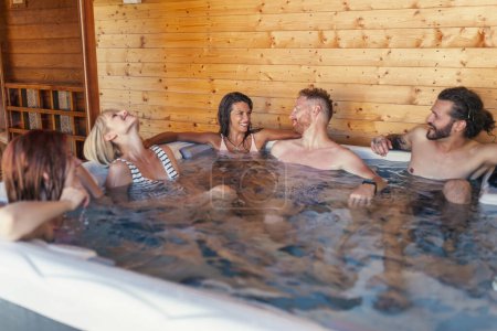 Téléchargez les photos : Groupe de jeunes amis joyeux se détendre dans un centre de spa hôtel spa bain à remous, s'amuser tout en vacances - en image libre de droit