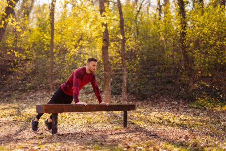 Téléchargez les photos : Homme travaillant à l'extérieur dans le parc d'entraînement de rue sur une journée d'automne ensoleillée, faire des pompes - en image libre de droit