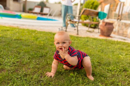 Foto de Hermoso niño jugando con sus padres en el patio trasero, arrastrándose por el césped - Imagen libre de derechos