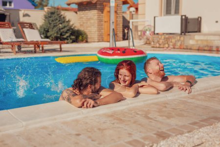 Group of friends having fun outdoors on a hot sunny summer day, hanging out and cooling down while swimming in the pool, relaxing on a summer vacation