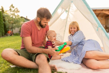 Photo for Young parents having fun camping in the backyard and playing with their little baby boy on a sunny summer day - Royalty Free Image