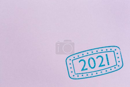 Foto de Hoja de estampado de tinta de papel morado; primer plano del sello de tinta con números 2021 que representa el próximo Año Nuevo en la página de papel morado con espacio para copiar - Imagen libre de derechos