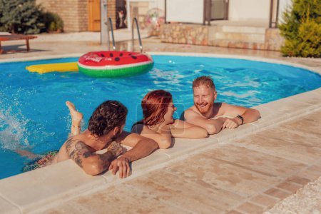 Foto de Grupo de amigos divirtiéndose al aire libre en un caluroso día soleado de verano, pasando el rato y enfriándose mientras nadan en la piscina, relajándose en unas vacaciones de verano - Imagen libre de derechos