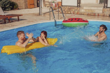 Gruppe fröhlicher junger Freunde hat Spaß beim Abkühlen und Planschen im Schwimmbad