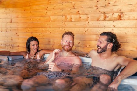 Foto de Grupo de alegres jóvenes amigos que se relajan en un spa del hotel centro de spa bañera de hidromasaje, divertirse mientras está de vacaciones - Imagen libre de derechos