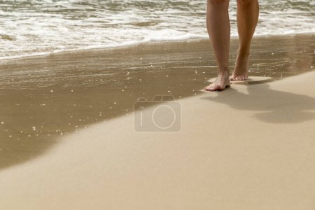 Téléchargez les photos : Femme marchant sur la plage, laissant des empreintes dans les cailloux - en image libre de droit