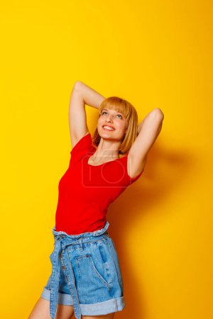 Téléchargez les photos : Joyeux belle jeune femme blonde portant des vêtements d'été à la mode sur fond jaune - en image libre de droit