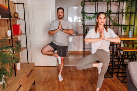 Foto de Pareja activa haciendo ejercicio juntos en casa, haciendo yoga como rutina de ejercicios matutinos - Imagen libre de derechos
