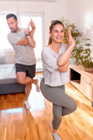Foto de Pareja joven haciendo ejercicio juntos en casa, haciendo yoga como rutina de ejercicios matutinos - Imagen libre de derechos