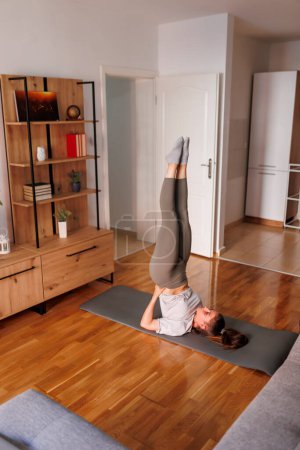 Téléchargez les photos : Active fit jeune femme en vêtements de sport faisant pose de yoga chandelier tout en faisant séance de yoga matin à la maison - en image libre de droit