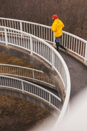 Photo for High angle view of an active man jogging on the bridge pathway as part of daily morning workout routine on a rainy cloudy day - Royalty Free Image
