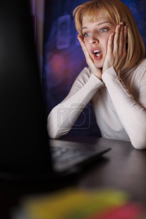 Photo for Woman sitting at her desk in home office using laptop computer stressed out while working late, having work related problems - Royalty Free Image