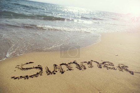 Foto de Palabra de verano escrita a mano en arena en la playa junto a la línea de flotación - Imagen libre de derechos
