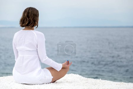 Foto de Mujer joven practicando yoga cerca de la playa de mármol en la isla de Tasos, Grecia. - Imagen libre de derechos