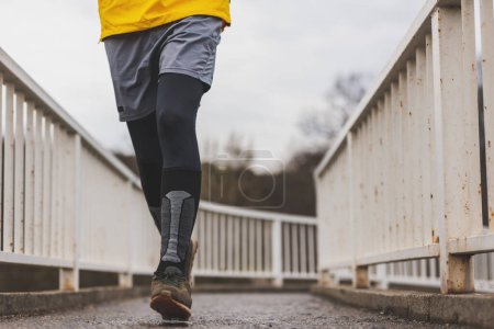 Téléchargez les photos : Détail de l'homme actif jogging le matin dans le cadre de la routine d'entraînement quotidien - en image libre de droit