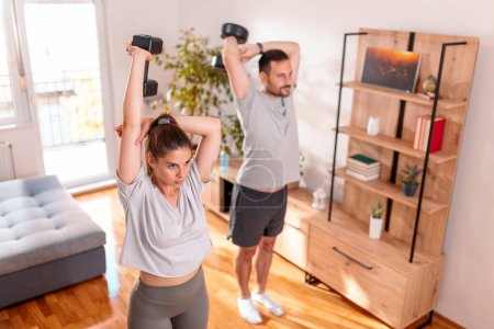Téléchargez les photos : Couple travaillant à la maison faisant des exercices de triceps à l'aide d'haltères - en image libre de droit