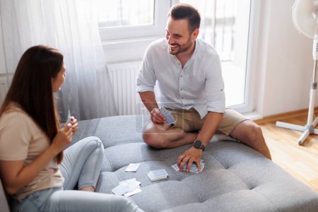 Hermosa pareja joven enamorada disfrutando de su tiempo libre en casa juntos y divirtiéndose jugando juegos de cartas