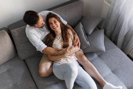 Foto de Vista de ángulo alto de una hermosa pareja joven enamorada relajándose en casa, acostada y abrazada en el sofá - Imagen libre de derechos