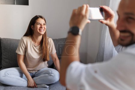 Téléchargez les photos : Couple s'amuser à la maison jeu de devinettes de mots, expliquer et deviner les mots d'une application de téléphone intelligent - en image libre de droit