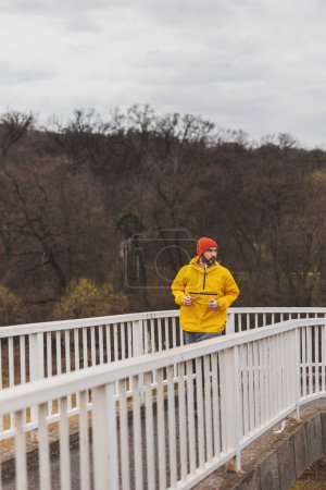 Téléchargez les photos : Homme actif faisant du jogging sur le sentier du pont par une journée d'automne nuageuse - en image libre de droit