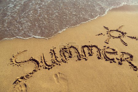 Téléchargez les photos : Mot été écrit à la main dans le sable sur la plage à côté de la ligne de flottaison - en image libre de droit