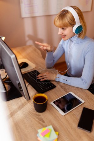 Téléchargez les photos : Femme assise à son bureau à la maison, ayant une conférence téléphonique tout en travaillant à distance de la maison - en image libre de droit