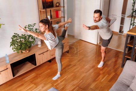 Téléchargez les photos : Vue en angle élevé de jeunes couples travaillant ensemble à la maison, faisant du yoga comme routine d'exercice matinal - en image libre de droit