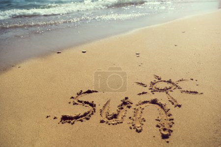 Photo for Word sun handwriten on  sand on the beach next to the water line - Royalty Free Image