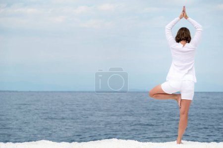Photo for Young woman practising yoga near marble beach on Thassos island, Greece. - Royalty Free Image