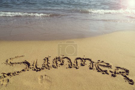 Téléchargez les photos : Mot été écrit à la main dans le sable sur la plage à côté de la ligne de flottaison - en image libre de droit