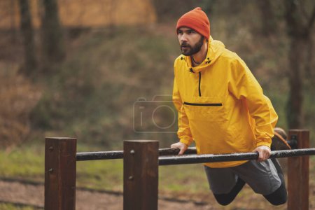 Photo for Active man exercising in a street workout park on a cloudy autumn day - Royalty Free Image