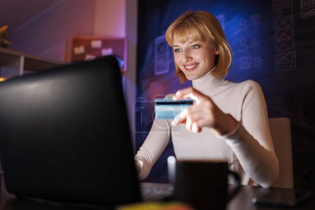 Téléchargez les photos : Femme utilisant un ordinateur portable faisant des achats en ligne insérant le numéro de carte de crédit tout en effectuant des paiements - en image libre de droit
