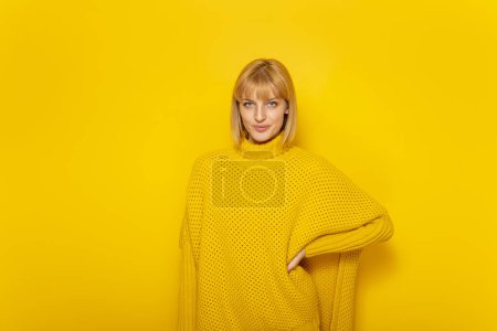 Photo for Beautiful young blond woman in yellow sweater smiling on yellow color background with copy space - Royalty Free Image