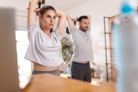 Téléchargez les photos : Couple travaillant à la maison faisant des exercices de triceps à l'aide d'haltères - en image libre de droit