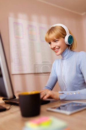 Téléchargez les photos : Femme freelance portant un casque travaillant dans le bureau à domicile à l'aide d'un ordinateur de bureau - en image libre de droit