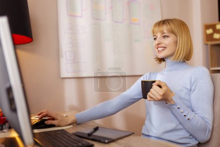 Téléchargez les photos : Développeur logiciel féminin boire du café tout en travaillant au bureau à domicile ; femme prenant une pause café - en image libre de droit