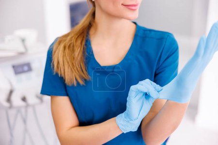 Téléchargez les photos : Médecin féminin portant des gants chirurgicaux protecteurs pendant son travail à l'hôpital ; dentiste portant des gants médicaux en latex avant la chirurgie buccale - en image libre de droit