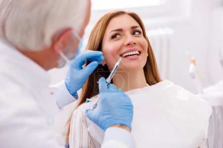 Photo for Detail of dentist applying local anesthetic to patient for numbing the pain before procedure; doctor applying lip fillers to female patient - Royalty Free Image