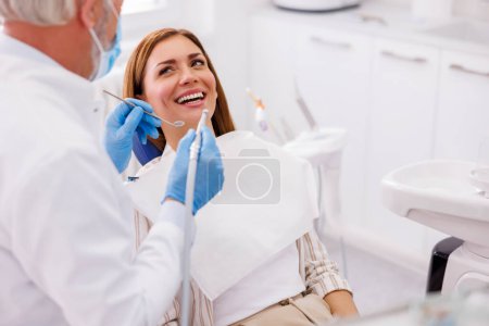 Foto de Dentista que fija el diente del paciente en la clínica dental usando taladro dental y espejo en ángulo - Imagen libre de derechos