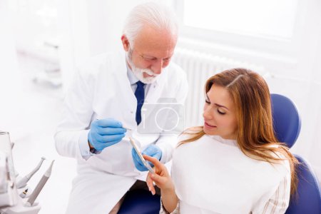 Foto de Dentista mostrando a paciente zirconio chapas dentales paleta de colores - Imagen libre de derechos