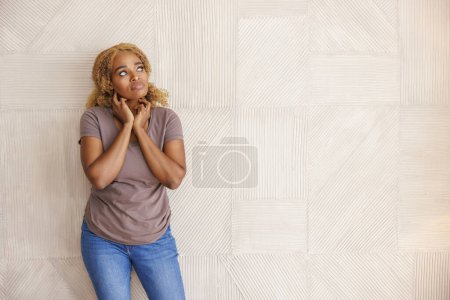 Foto de Retrato de una hermosa joven africana de pie frente a una pared de hormigón con la cabeza en las manos seria y pensativa con espacio para copias - Imagen libre de derechos