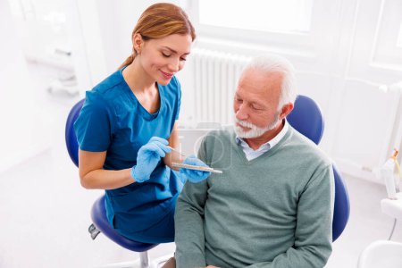 Téléchargez les photos : Dentiste montrant au patient zirconium placages dentaires palette de couleurs - en image libre de droit