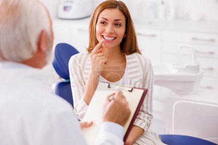 Téléchargez les photos : Femme ayant un examen dentaire au cabinet du dentiste, consulter un médecin au sujet des procédures nécessaires - en image libre de droit