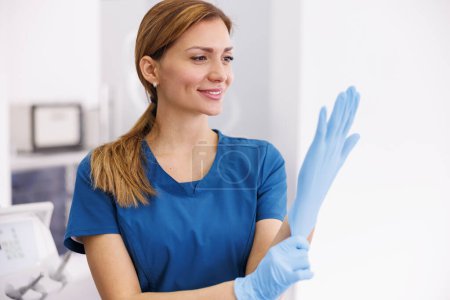 Téléchargez les photos : Médecin féminin portant des gants chirurgicaux protecteurs pendant son travail à l'hôpital - en image libre de droit