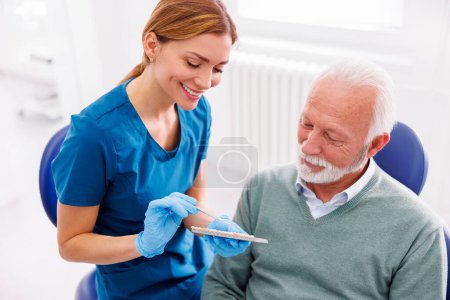 Téléchargez les photos : Dentiste montrant la palette de couleurs de placages dentaires de zirconium au patient - en image libre de droit