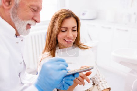 Téléchargez les photos : Dentiste montrant au patient zirconium placages dentaires palette de couleurs - en image libre de droit