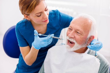 Dentist applying local anesthetic to patient for numbing the pain before procedure