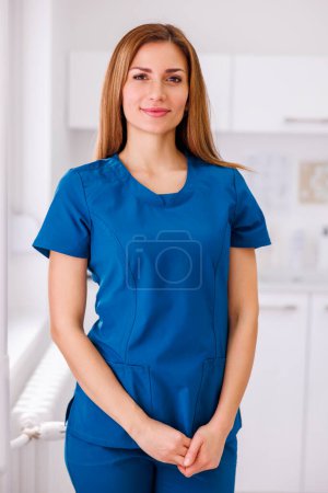 Photo for Portrait of young female doctor wearing uniform standing in ER and smiling - Royalty Free Image