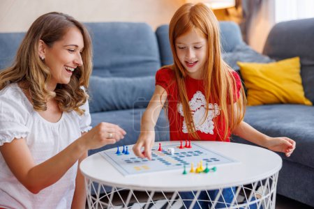 Téléchargez les photos : Belle mère et fille s'amusent à jouer au jeu de société de ludo tout en passant du temps libre ensemble à la maison - en image libre de droit